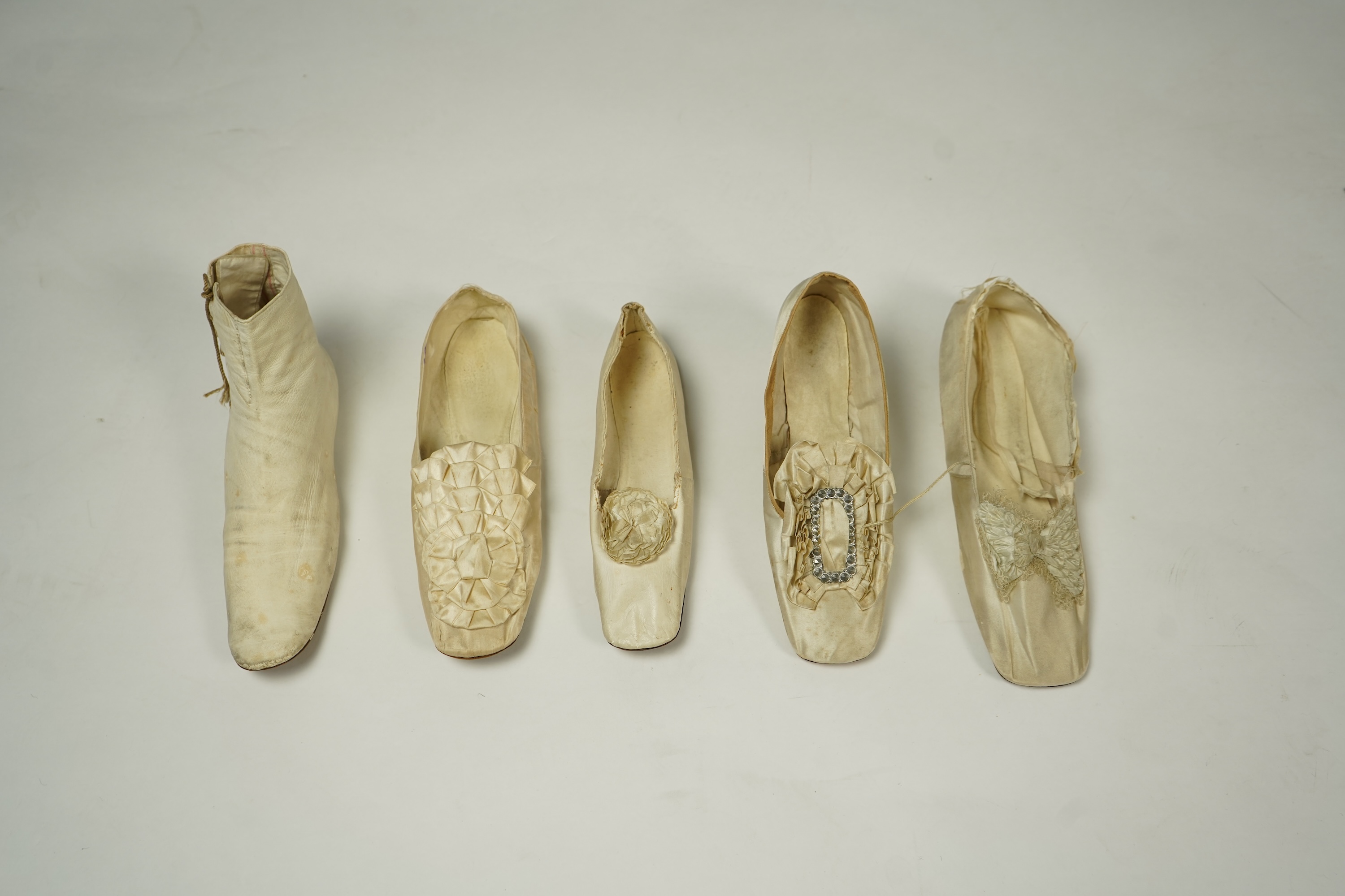 A 19th century hand made cream kid leather ladies ankle boot and four differing cream silk and satin single wedding shoes. All with leather soles. Possibly a traveller's sample range. Boots 24.5cm long (heel to toe). Con